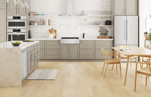 Modern kitchen with light wood flooring, gray cabinetry, stainless steel appliances, and a dining table with chairs