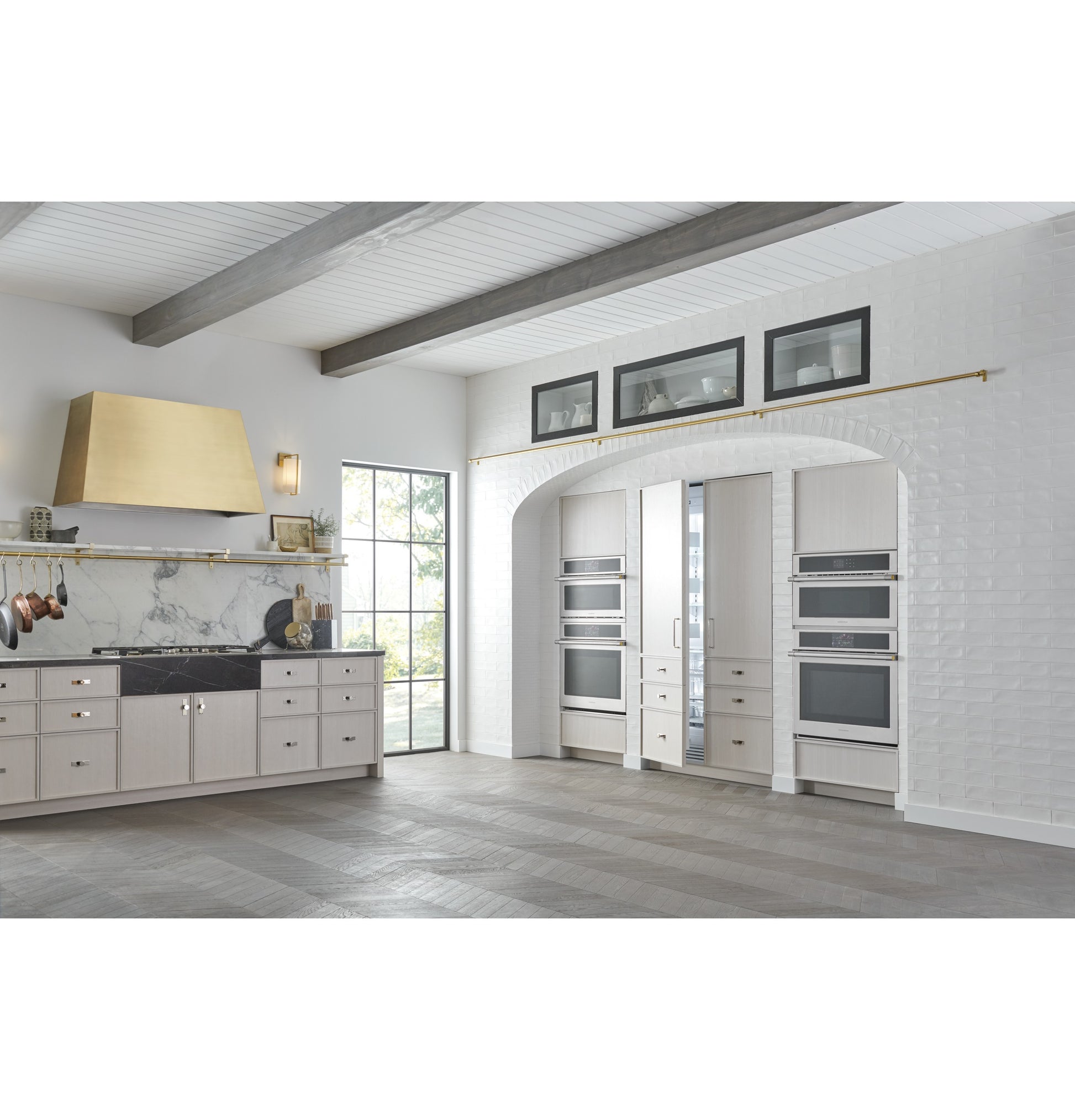 Contemporary kitchen with multiple built-in wall ovens set in white brick cabinetry and light wood flooring in appliances collection