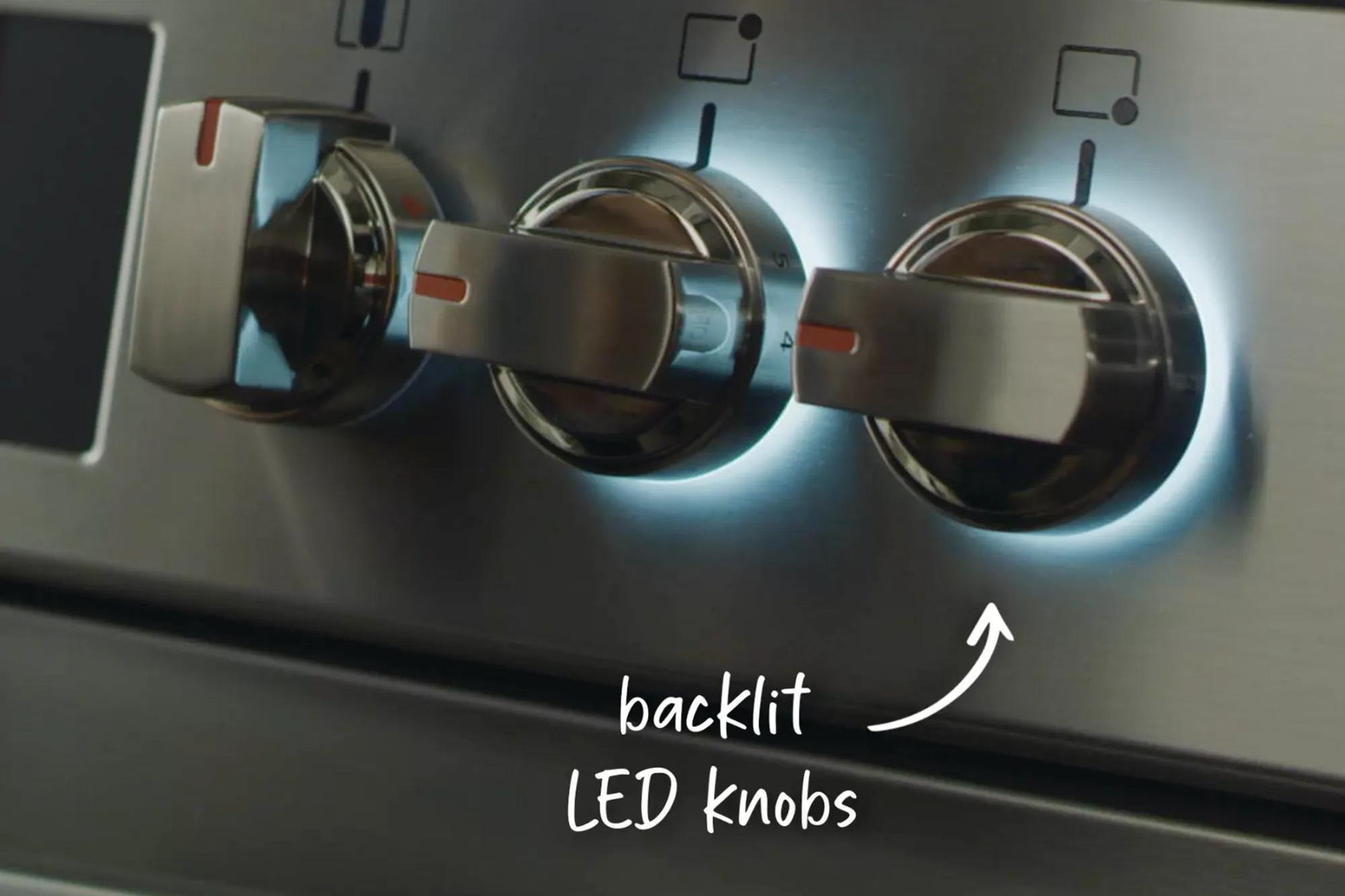 Close-up of backlit LED stainless steel control knobs on modern kitchen gas range from appliances and kitchenware collection