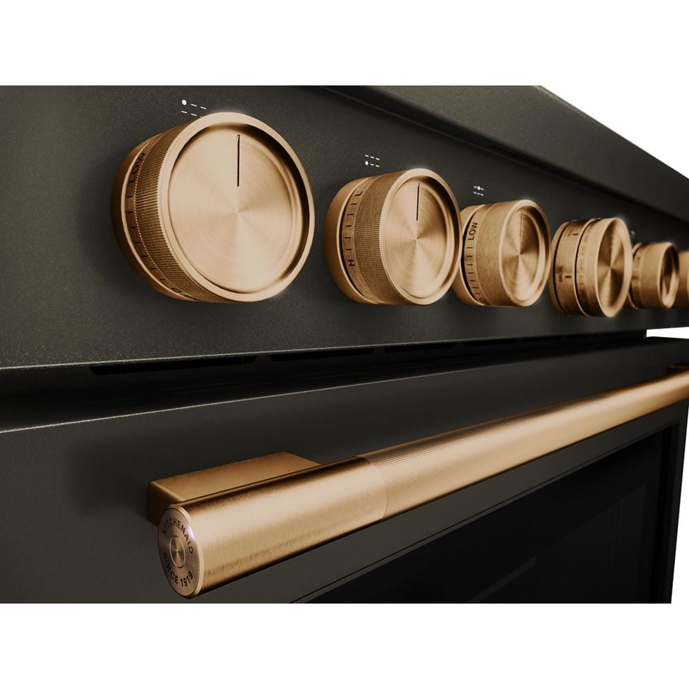 Close-up of bronze control knobs and handle on black dual fuel commercial-style range from KitchenAid collection