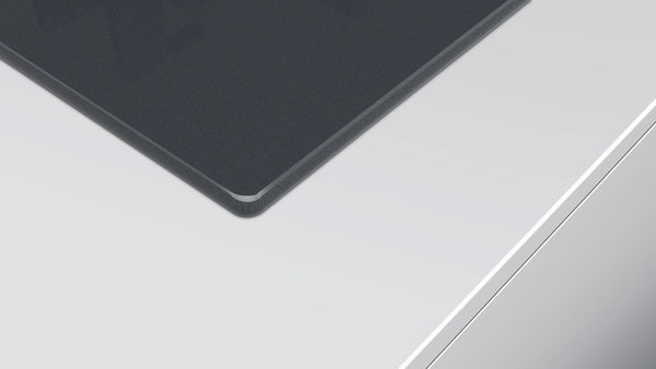 Corner view of dark silver tempered glass surface on a modern cooktop for home improvement and Bosch appliances