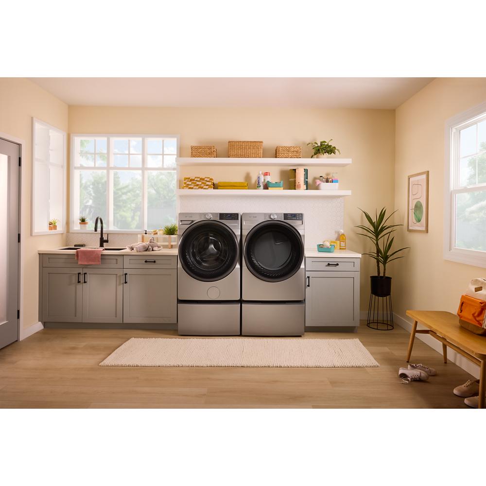 Modern laundry room with matching gray front load washer and dryer, sleek cabinetry, and natural light from windows