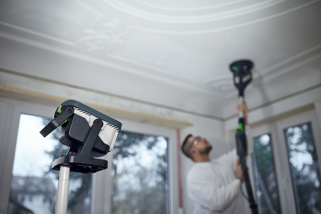 Cordless Festool Syslite work light mounted on adjustable pole for versatile indoor home improvement tasks