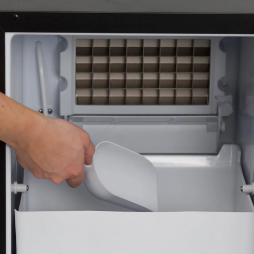 Hand scooping ice inside a built-in or freestanding ice maker from the Freezers & Ice Makers collection