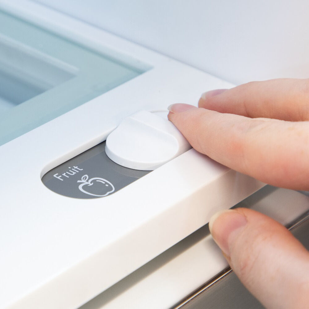 Close-up of hand adjusting fruit freshness control knob inside refrigerator door in kitchen appliances collection