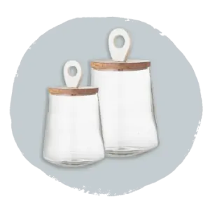 Two clear glass storage jars with wooden lids and loop handles, displayed against a light gray circular background.