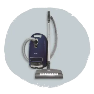 Dark blue canister vacuum cleaner with a flexible hose and silver adjustable wand, shown against a light gray circular backdrop.