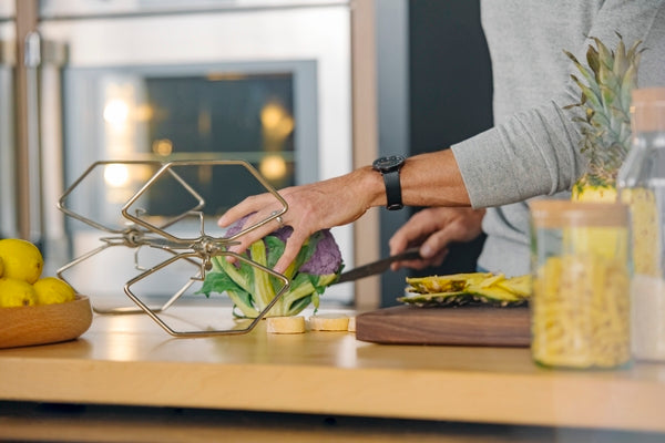 Person preparing vegetables near a stainless steel single wall oven in modern kitchen and home improvement setting