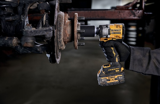 Compact yellow and black cordless impact wrench with hog ring and ergonomic grip used in automotive repair tasks