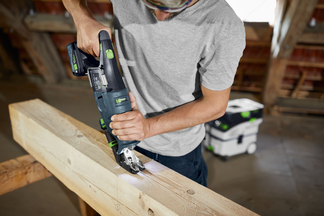 User operating Festool cordless reciprocating saw cutting through thick wooden beam in workshop for home improvement project
