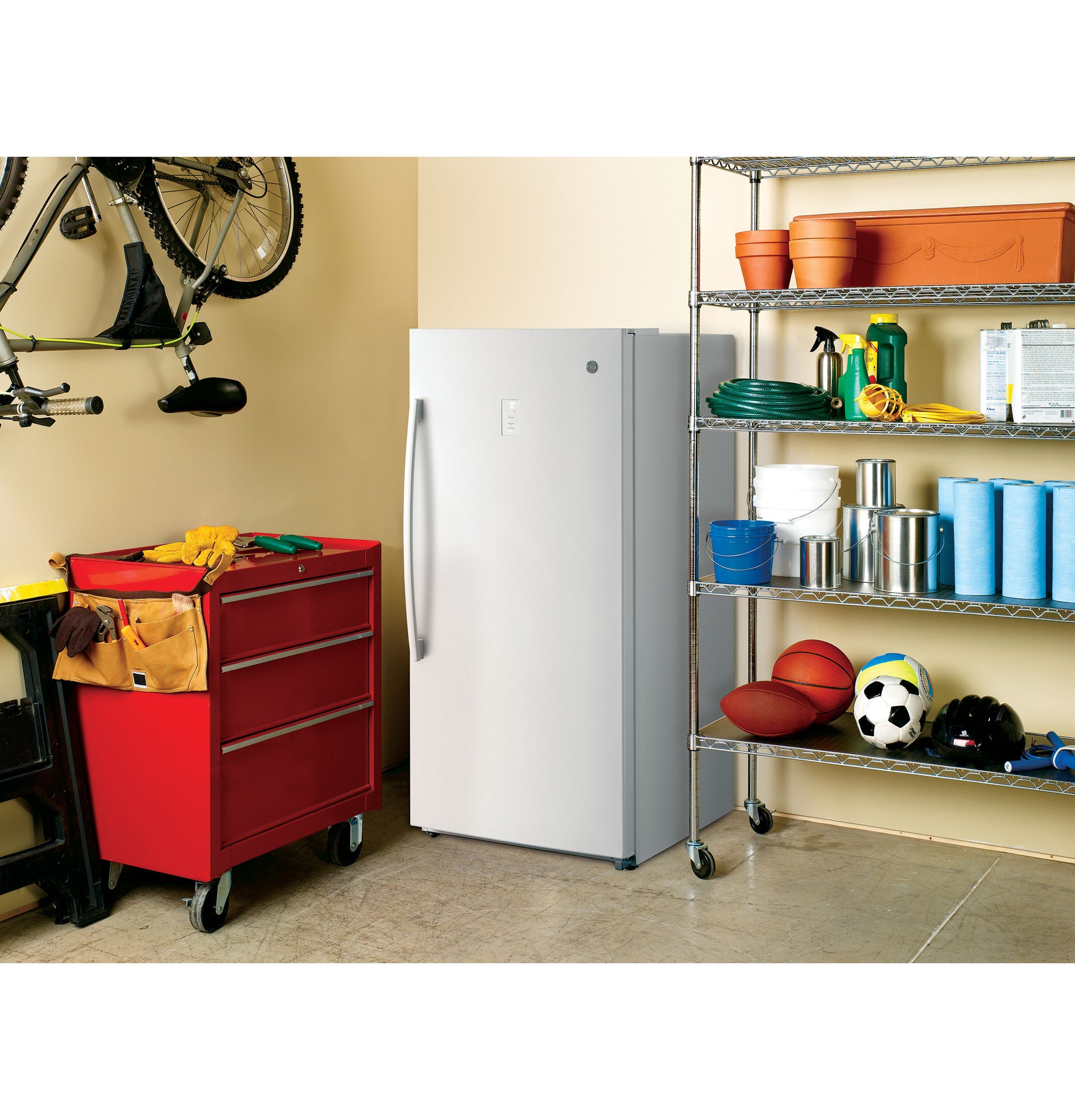 White frost-free upright freezer with vertical handle in organized garage setup with tools and sports equipment nearby