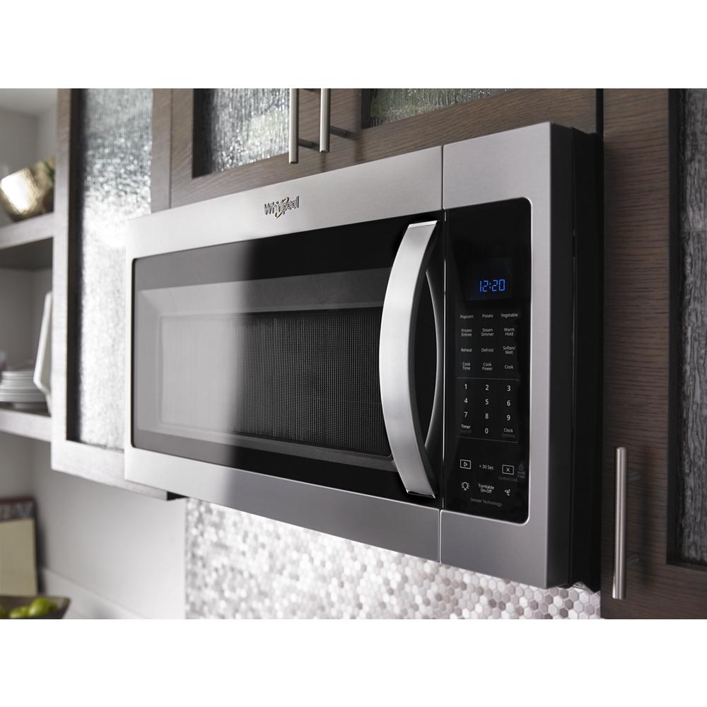 Stainless steel Whirlpool microwave with sensor cooking, digital keypad, and blue LED clock in modern kitchen setting