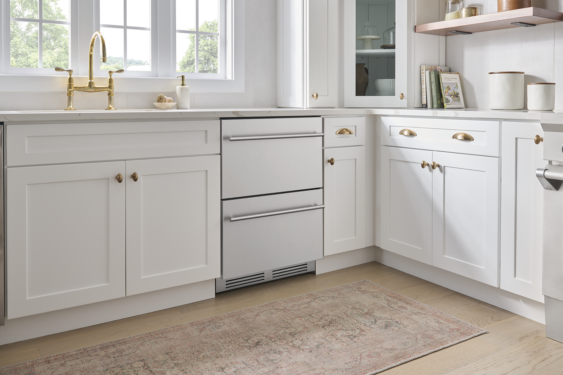 Under-counter stainless steel refrigerator drawers integrated in bright white kitchen cabinetry for modern appliance use