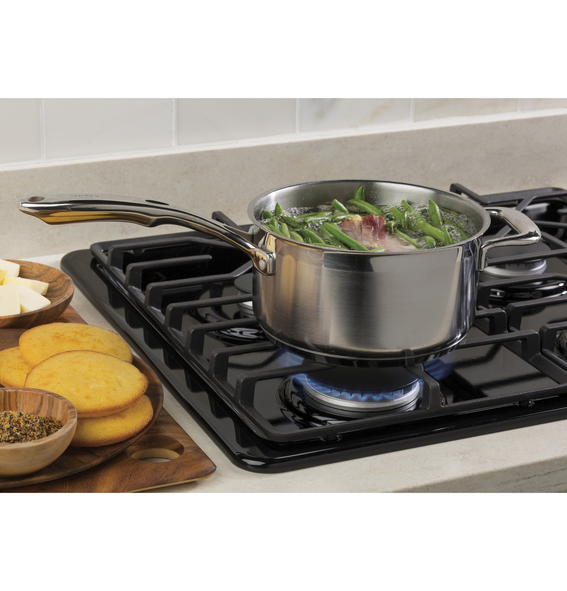 Stainless steel saucepan boiling vegetables on black built-in gas cooktop with dishwasher-safe grates in Kitchen & Kitchenware