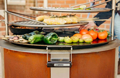 Hot-rolled carbon steel searplate griddle with vegetables cooking over fire pit for outdoor living and patio collections