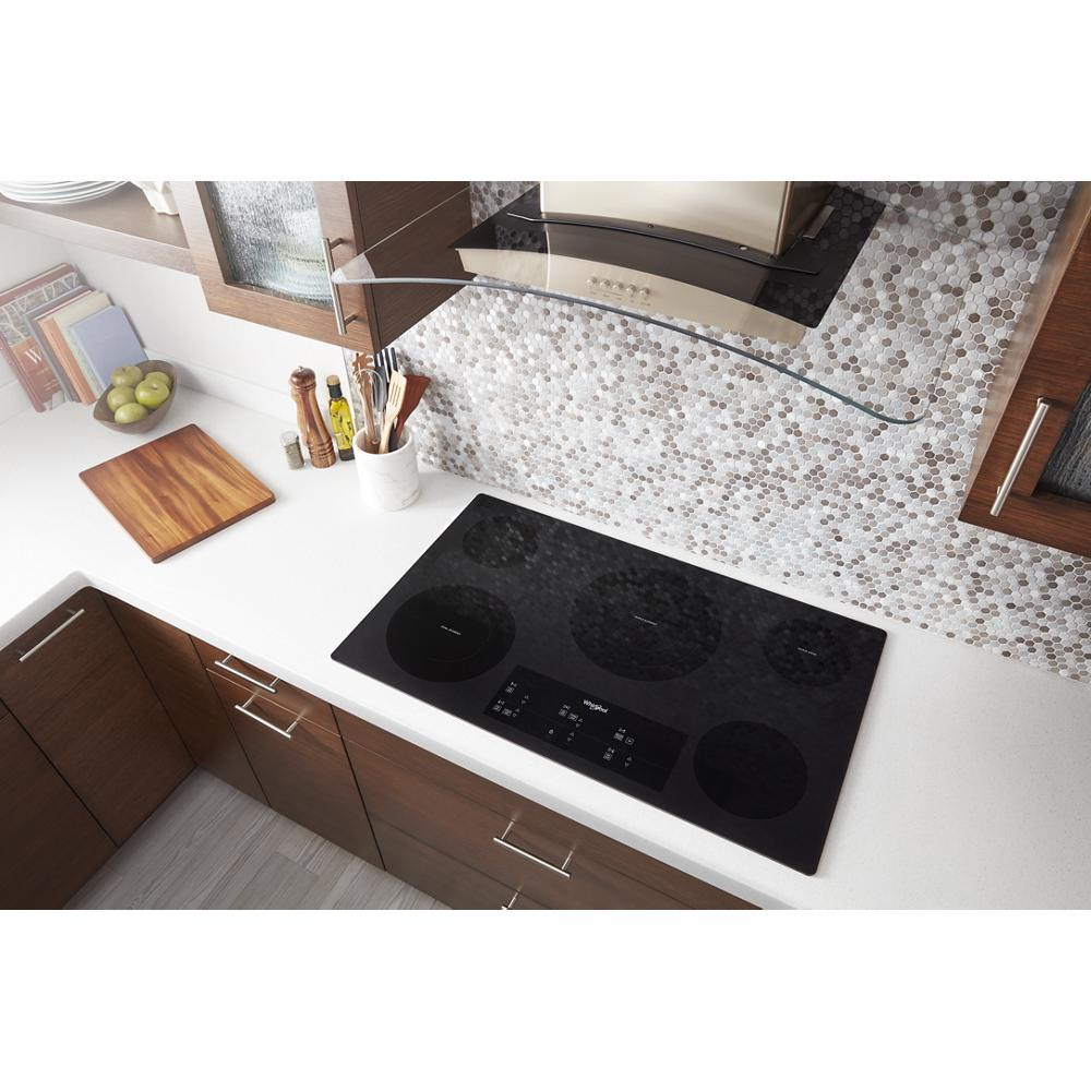 Black electric ceramic glass cooktop with four radiant heating elements installed in modern kitchen countertop