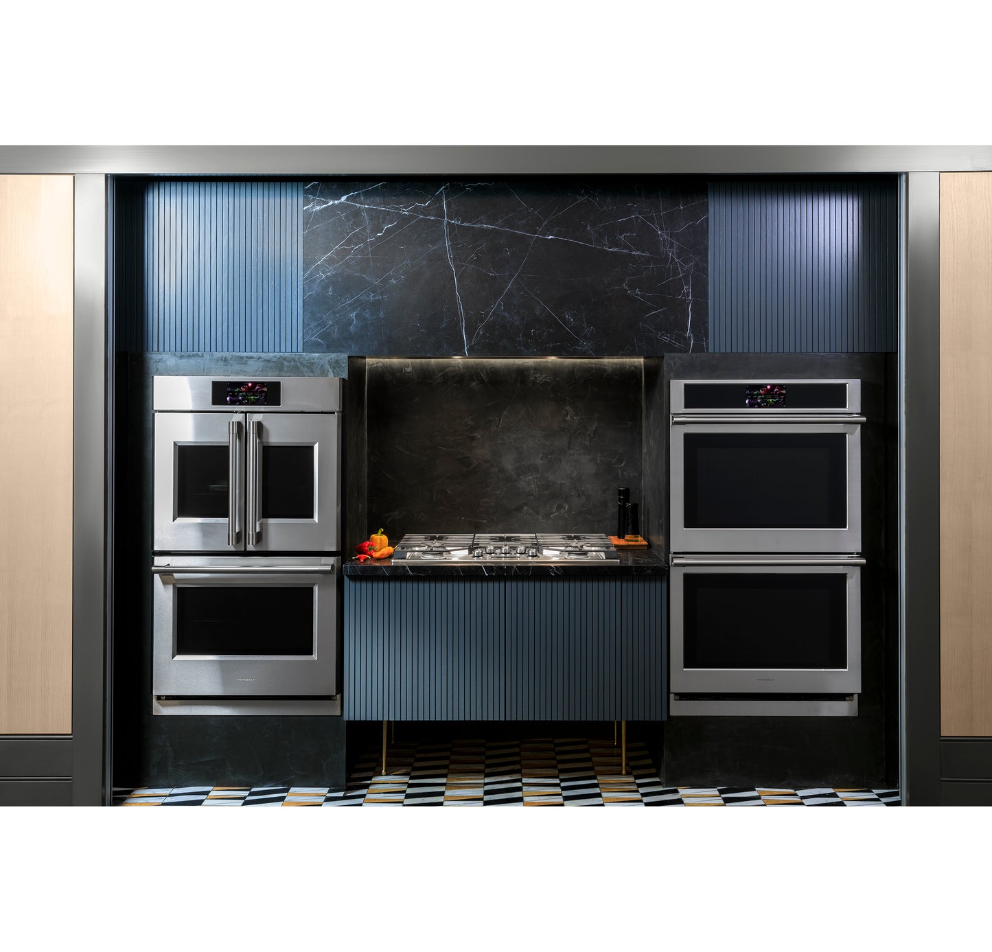 Stainless steel double wall ovens installed in modern kitchen with black and blue cabinetry and gas cooktop center
