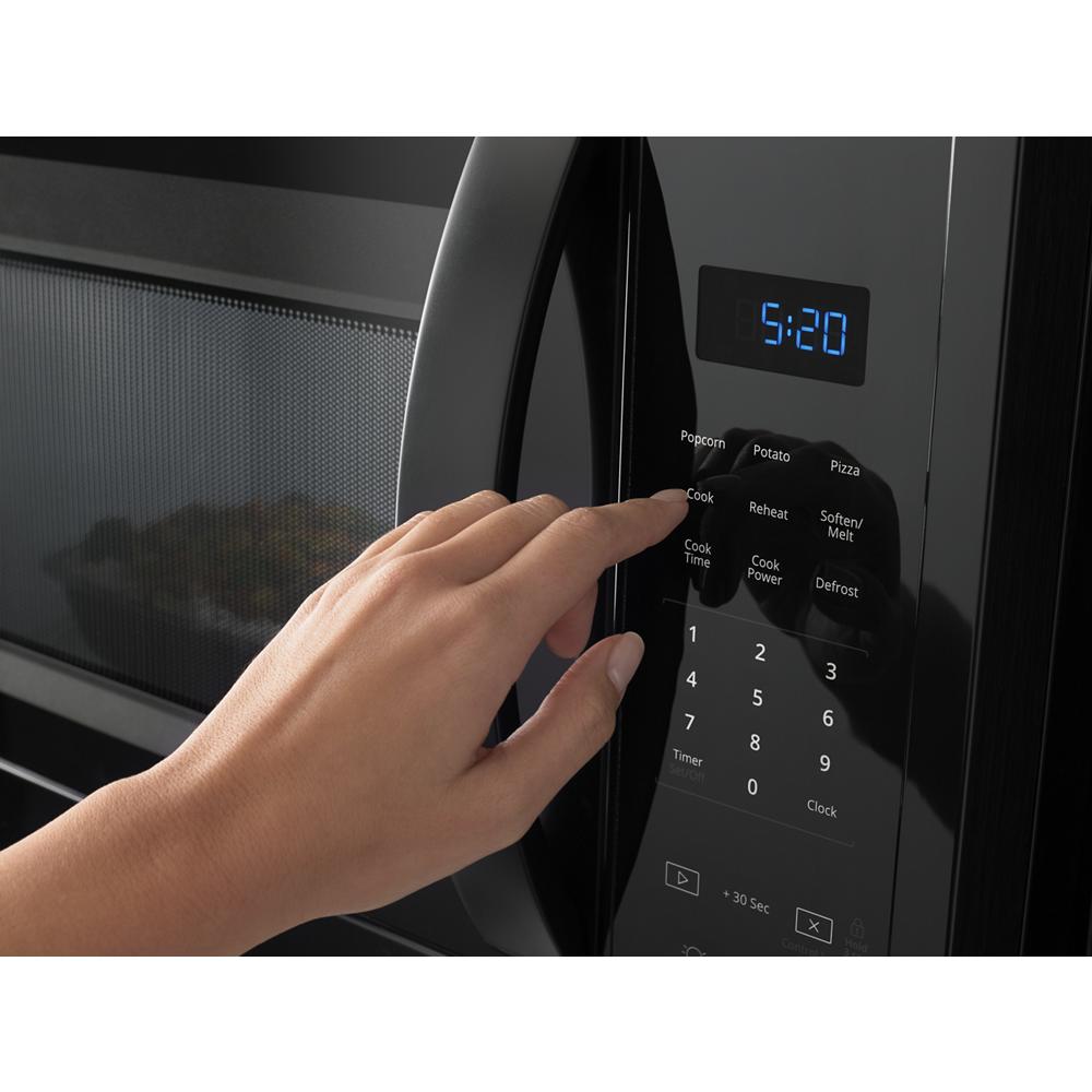 Hand pressing electronic touch control panel on black microwave from kitchen appliances collection