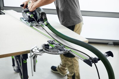 Person using Festool plunge cut track saw with dust extraction on wood panel for precise cuts in power tools collection