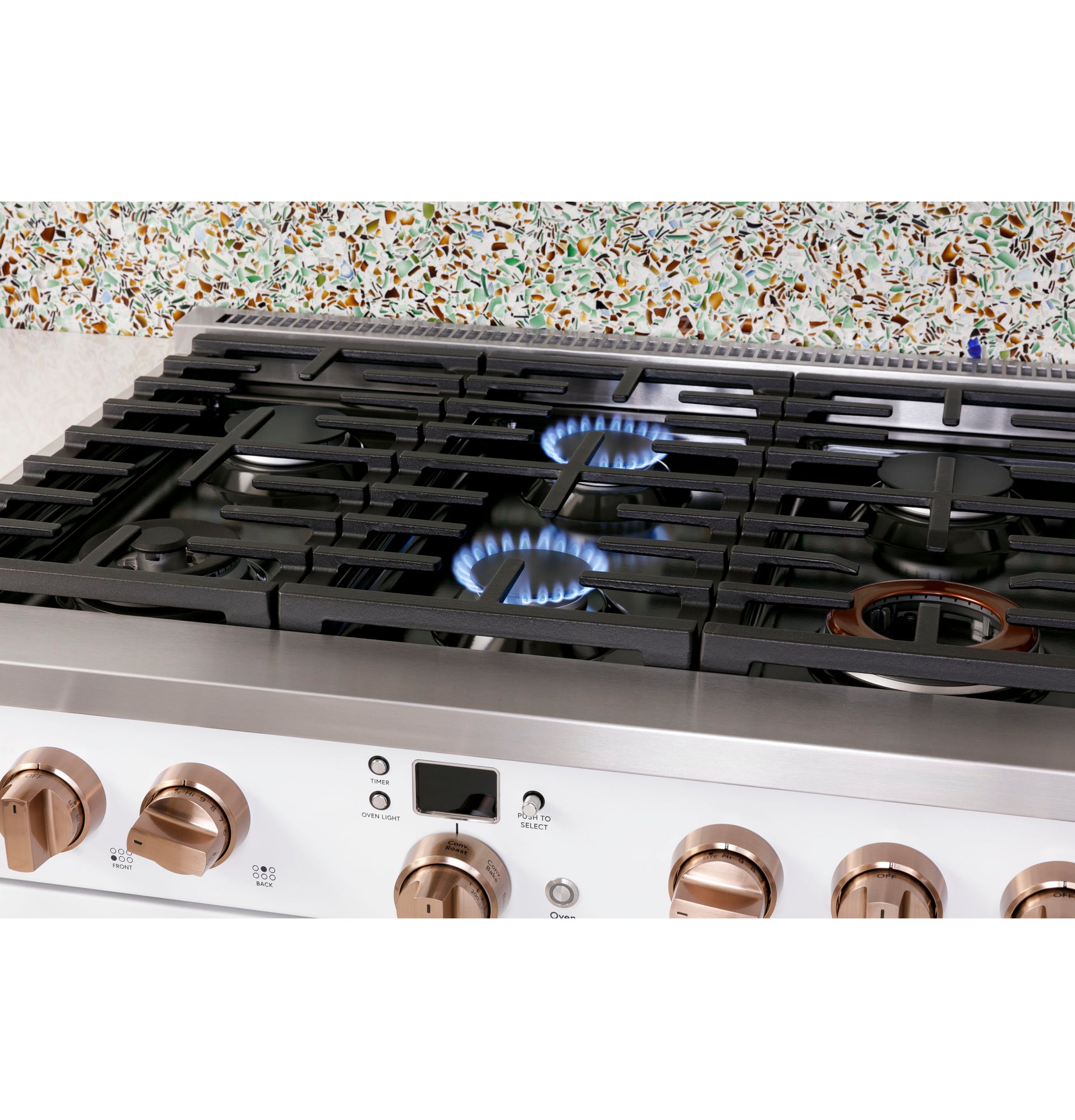 Stainless steel commercial-style range cooking two burners with bronze control knobs in modern kitchen setting