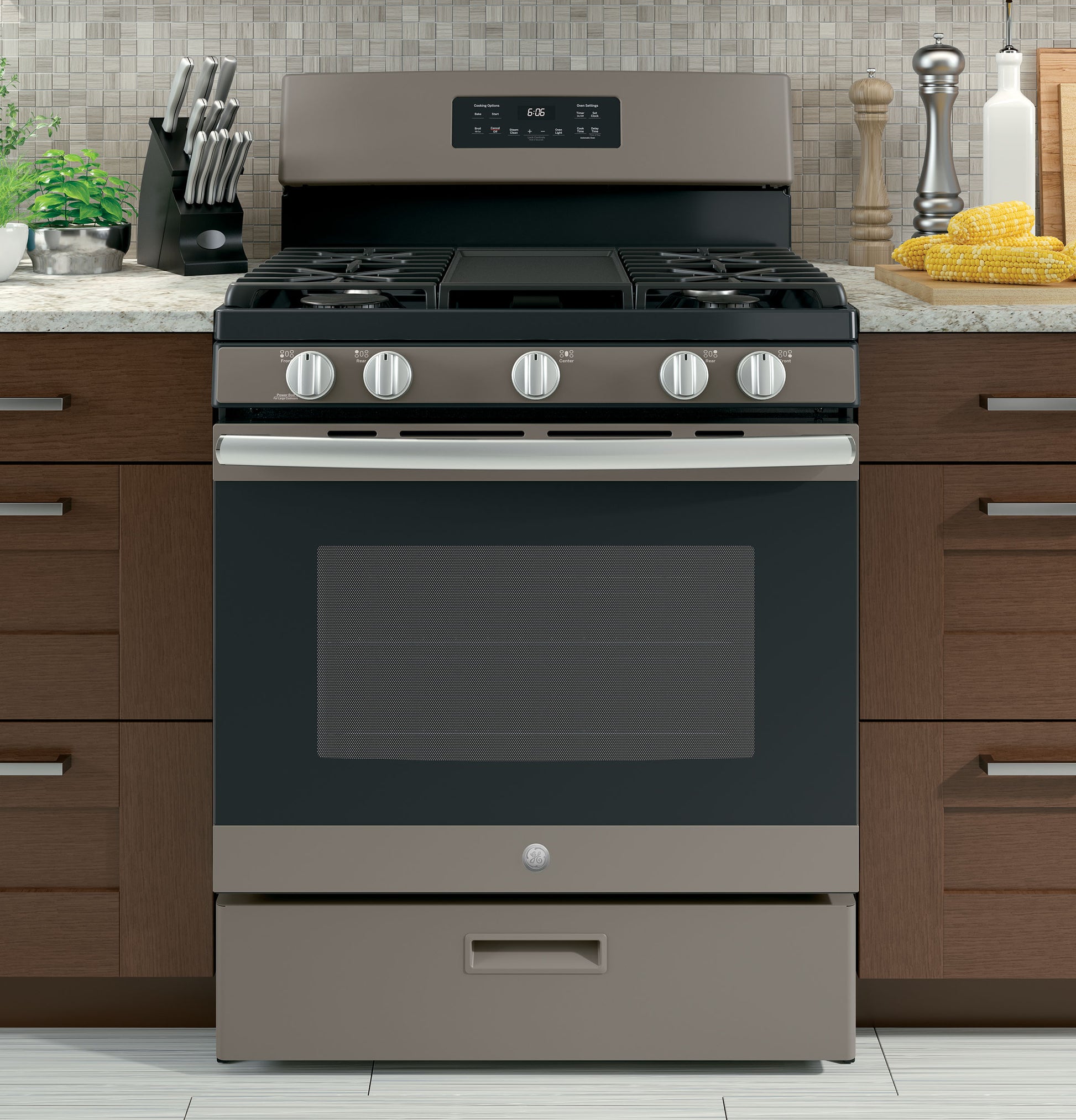 Front view of a stainless steel free-standing gas range with five burners and control knobs in a modern kitchen setting