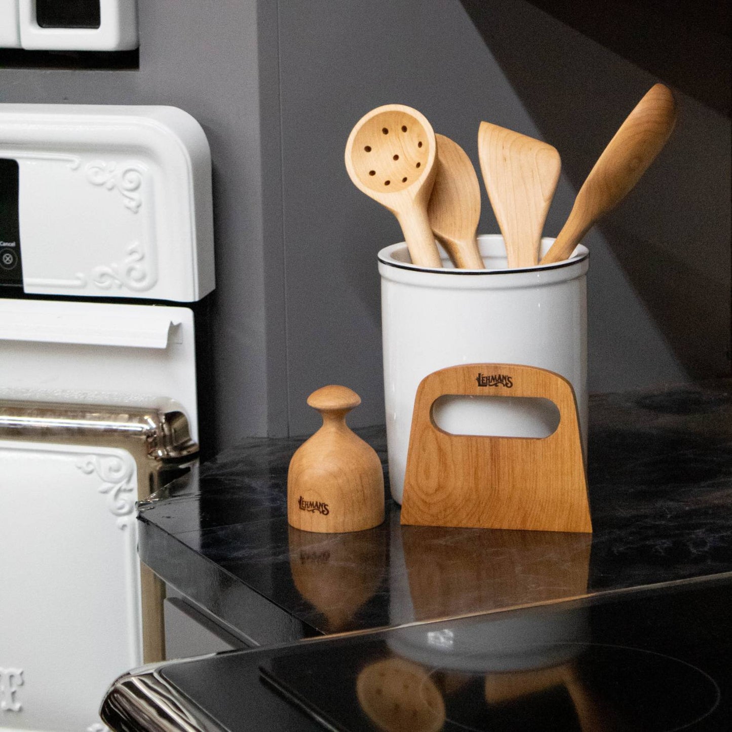 Variety of handcrafted solid American Hard Maple utensils displayed in white crock and wooden stand in kitchenware collection