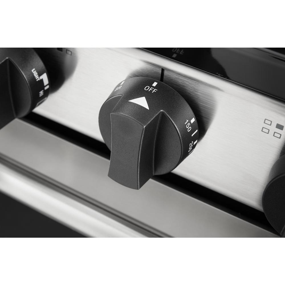 Close-up of a black control knob set to off on a stainless steel freestanding gas range panel for kitchens and appliances.