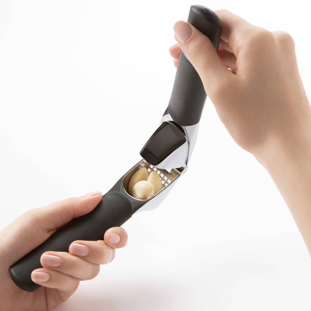 Hands using large capacity garlic press with black ergonomic handles for kitchenware and home tools under $50 collections