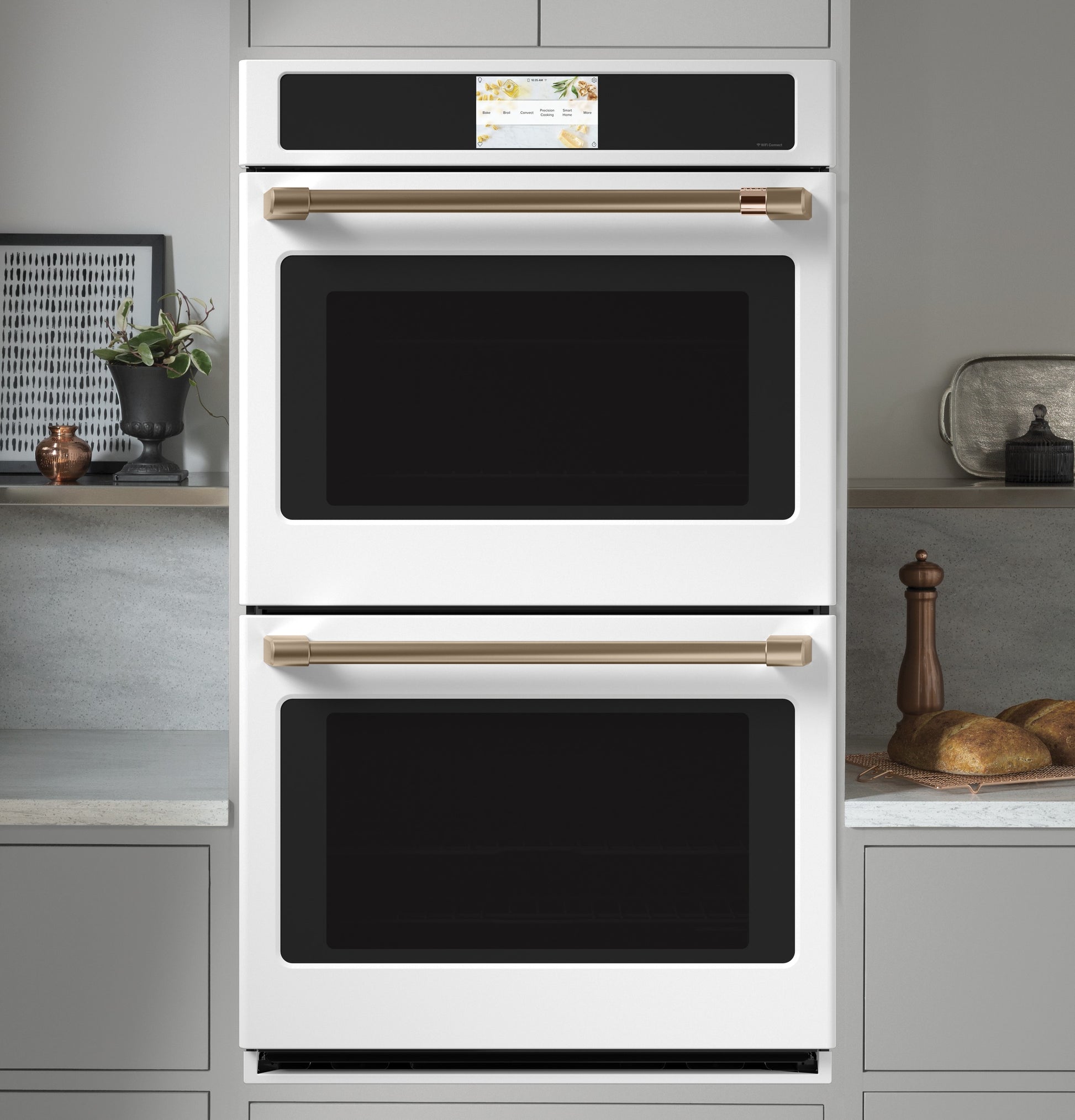 White built-in convection double wall oven with smart touchscreen and bronze handles in modern kitchen setting