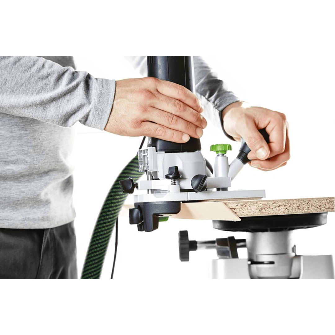 Person using an edge banding router with Festool tool accessories on a wood panel in woodworking workshop