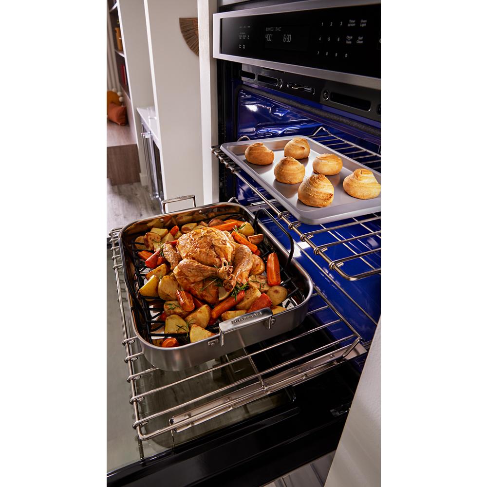 Open single wall oven with roasted chicken and vegetables on lower rack and fresh baked rolls on upper rack