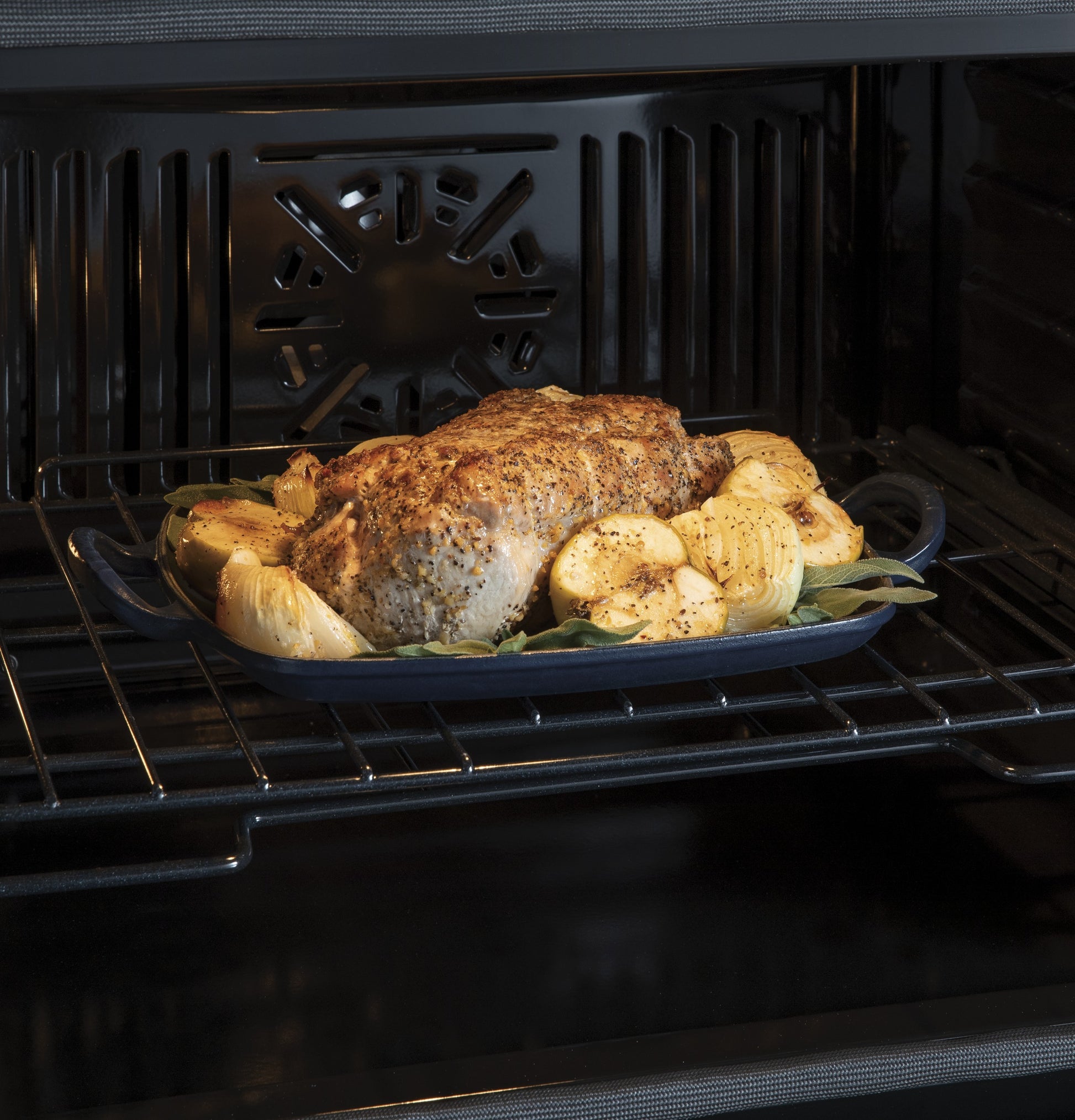Roast chicken and seasoned vegetables cooking inside a convection wall oven from the Double Wall Ovens collection