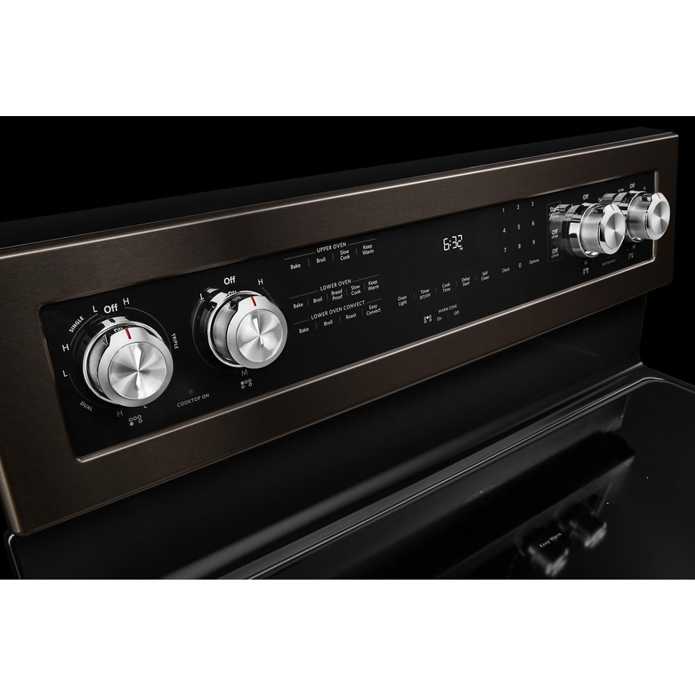 Close-up of a black electric range control panel with silver knobs and digital display in kitchen appliances category