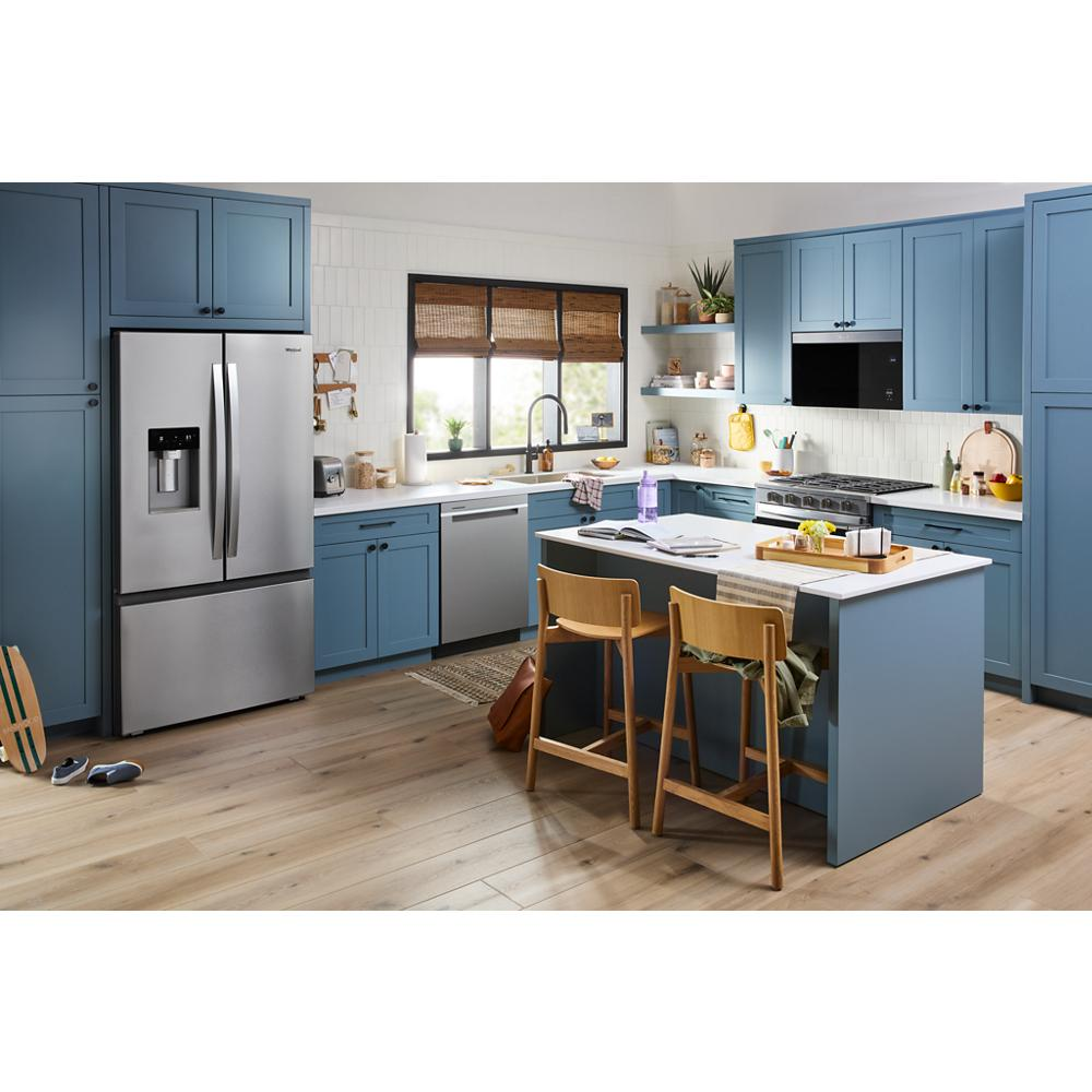 Modern kitchen with blue cabinets, stainless steel French door refrigerator, center island, and natural light from window