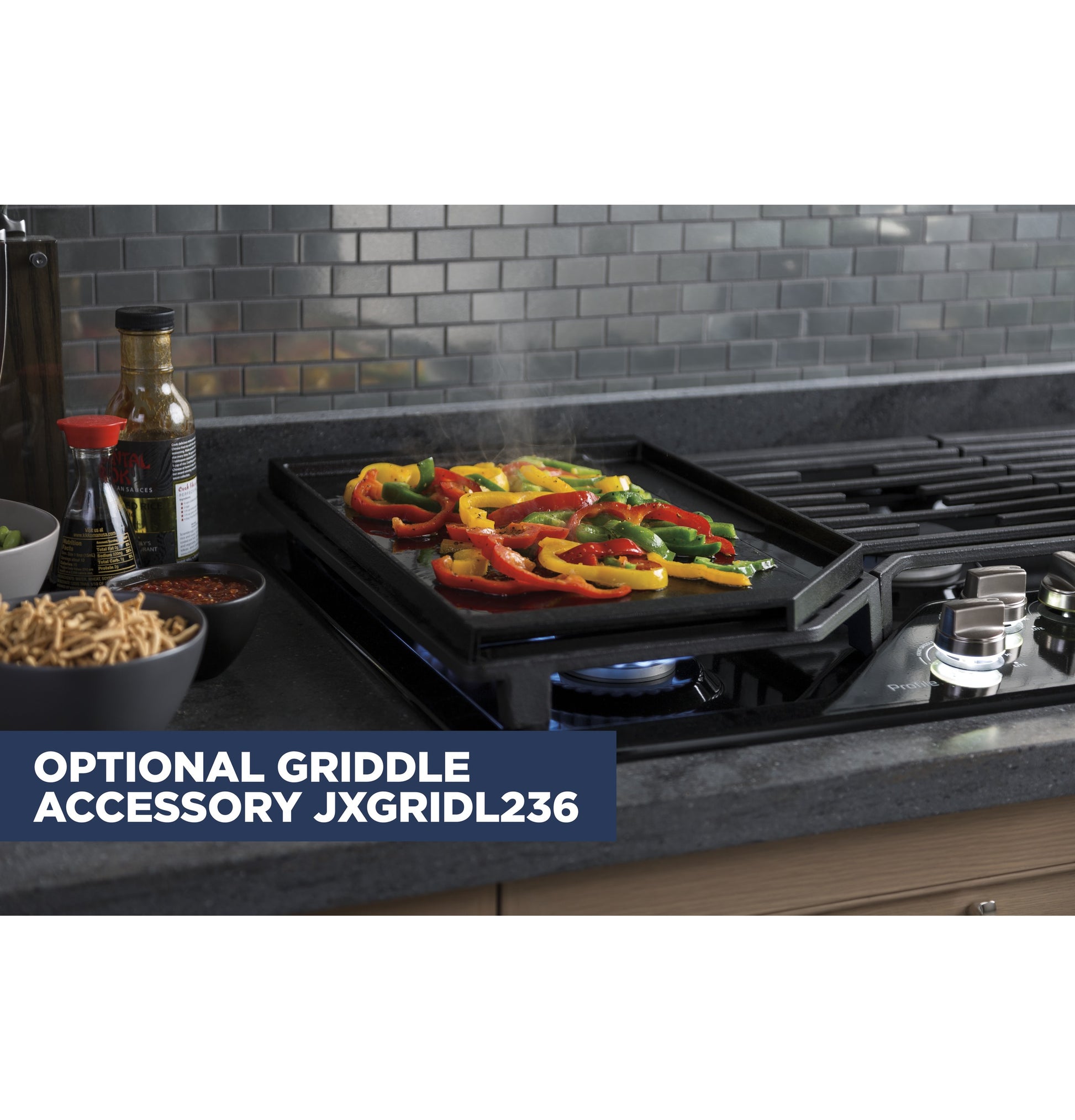 Colorful bell peppers grilling on a black optional griddle accessory on a built-in five-burner gas cooktop in kitchen setting