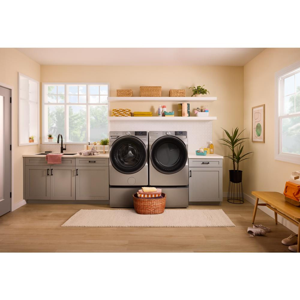 Matching gray smart front load electric washer and dryer set in a bright laundry room with beige walls and wood flooring
