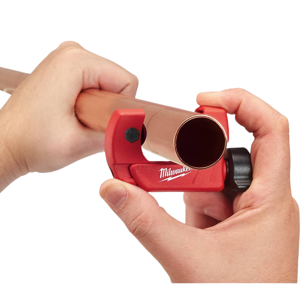 Hands using red Milwaukee mini tubing cutter to trim copper pipe for precise home improvement plumbing tasks