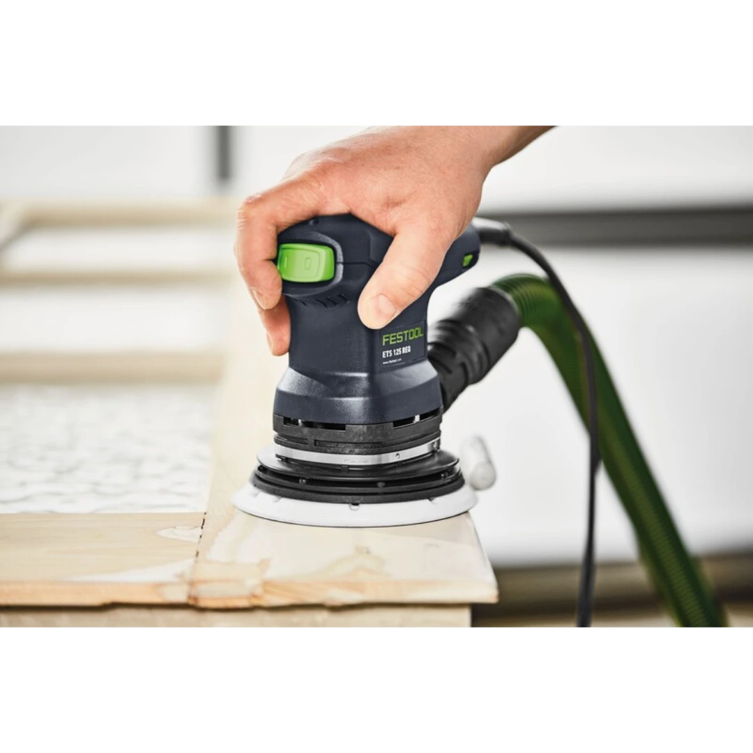 Person using a Festool random orbital sander with dust extraction on a wooden surface for woodworking tool tasks