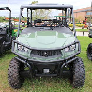 Front view of a green John Deere crossover utility vehicle with rugged tires parked on grass outdoors