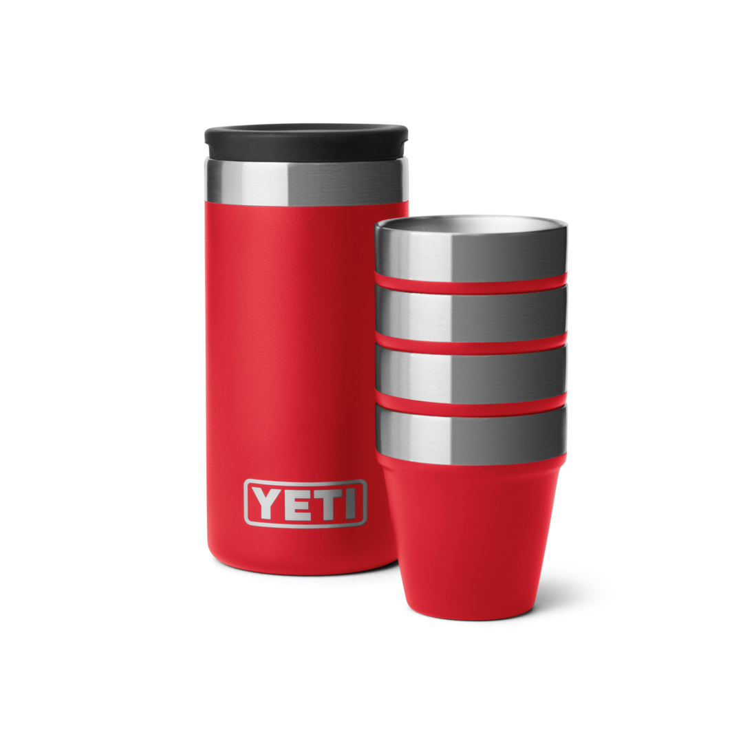 Red insulated carrying case next to four stacked stainless steel shot glasses with red bands for durable drinkware use