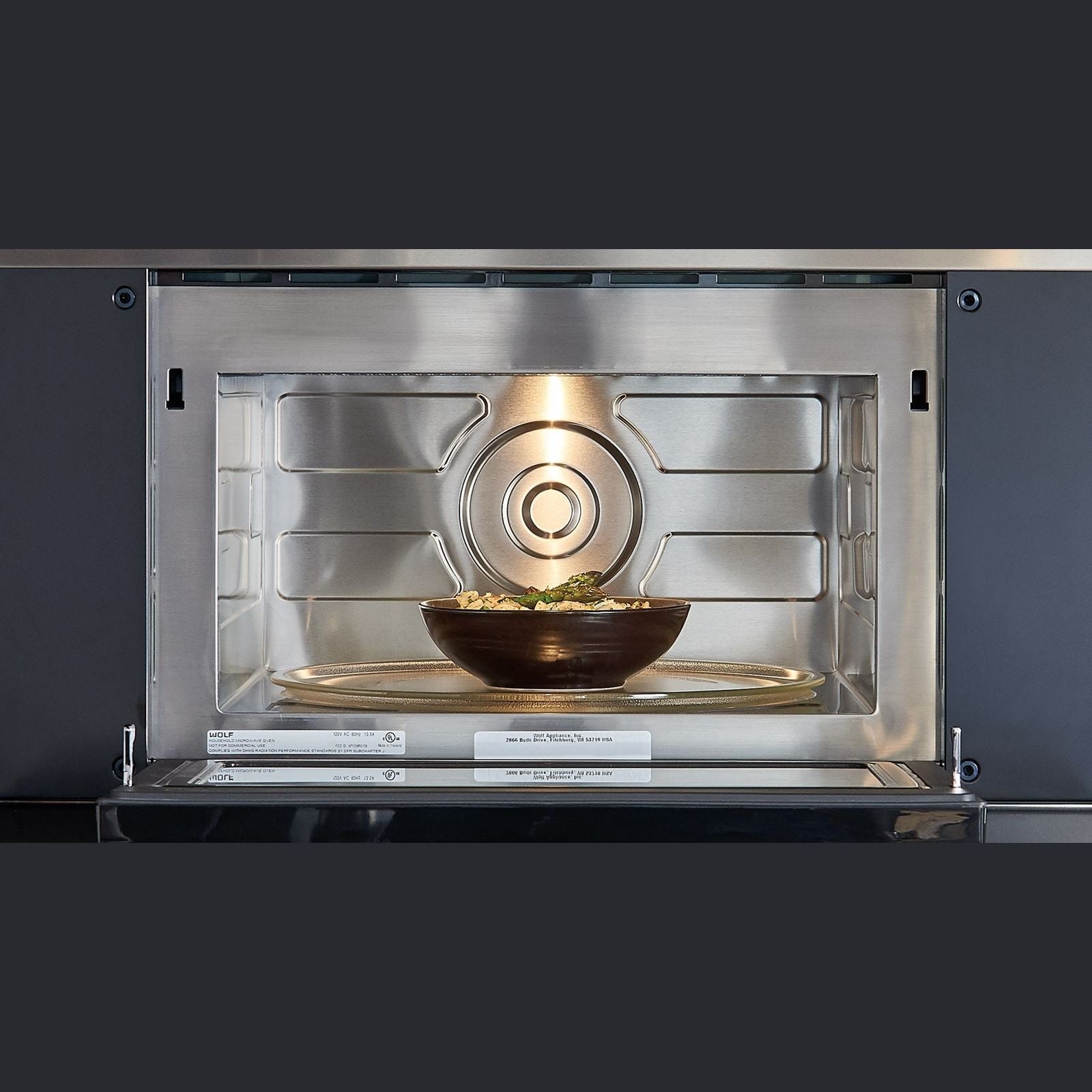 Stainless steel transitional microwave with drop down door interior showing a bowl of food on glass tray for home improvement kitchens