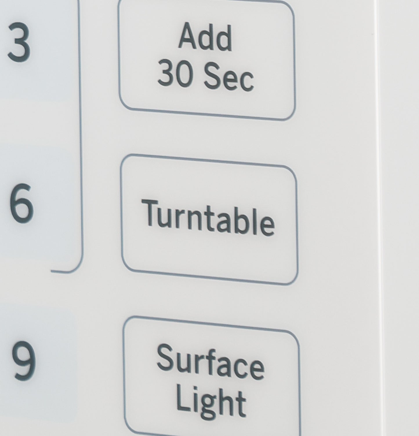 Close-up of white microwave oven control panel buttons for Add 30 Sec, Turntable, and Surface Light functions in kitchen appliance collection