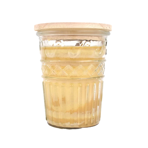Glass jar candle with textured design and wooden lid containing creamy glazed banana bread scented wax