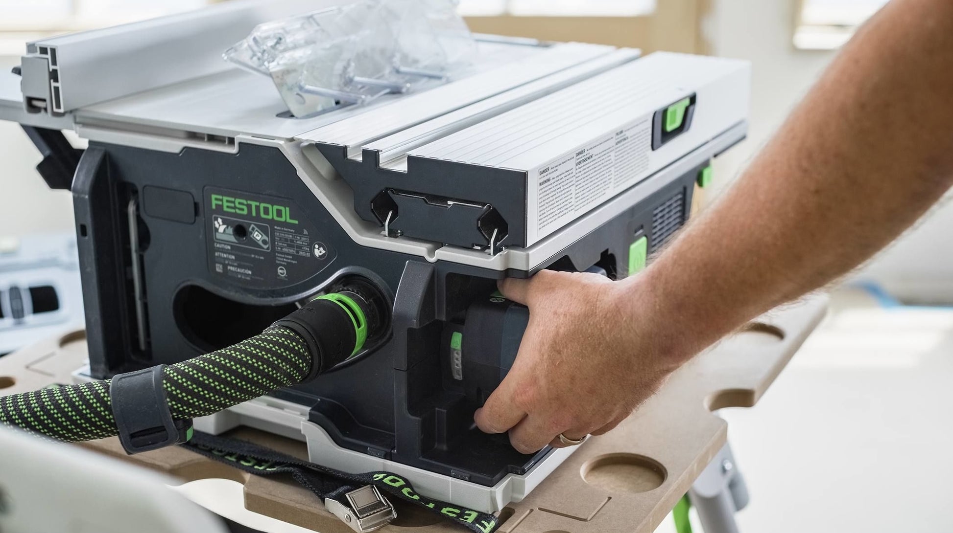 Hand adjusting a compact cordless table saw from Festool, part of battery-powered power tools and saws collection