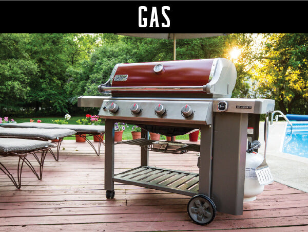 Gas grill with a red hood and four control knobs standing on a wooden deck near a pool with patio furniture and lush greenery in the background.