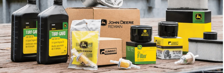 Various maintenance parts and filters for outdoor equipment, including oil containers, air and fuel filters, and packaged replacement components arranged on a wooden surface.