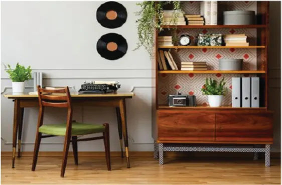 Mid-century modern home office corner with a wooden desk and chair, vintage typewriter, decorative plants, two vinyl records on the wall, and a wooden shelving unit filled with books and decor.
