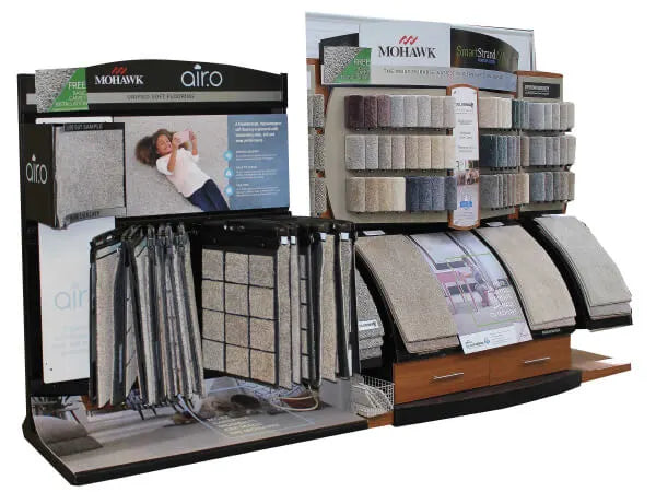 Display featuring various carpet samples in neutral tones arranged on panels and hanging swatches, showcasing flooring options for home improvement projects.