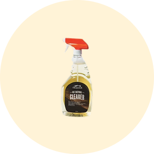 Clear spray bottle with an orange nozzle containing all-purpose cleaner and a dark label with white and orange text on a pale beige circular background.