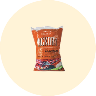 Bag of Traeger Hickory wood pellets with bold orange and white text, featuring grilling imagery on a beige circular background.